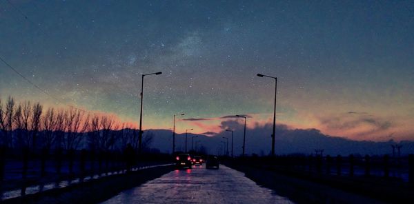 Road amidst trees against sky at night during winter