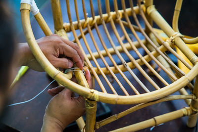 Close-up of man making wicker chair