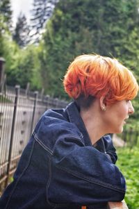 Side view portrait of man with arms raised against trees
