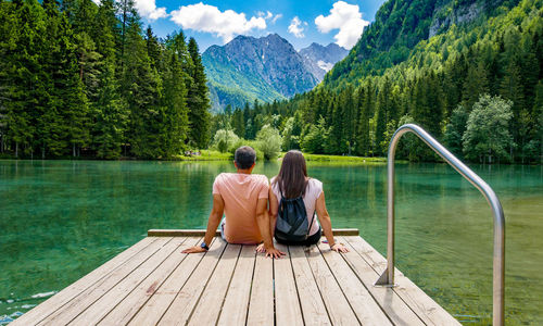 Rear view of people looking at lake against mountains