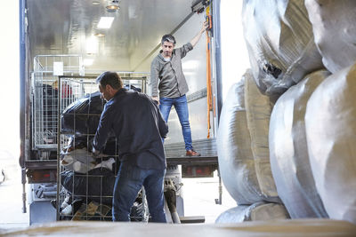 Mature coworkers unloading semi-truck at warehouse