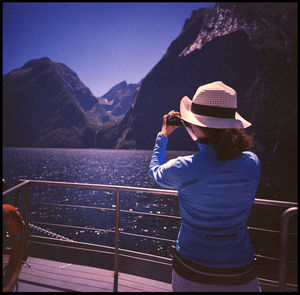 Rear view of woman standing by railing against mountain