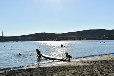 People on beach against clear sky