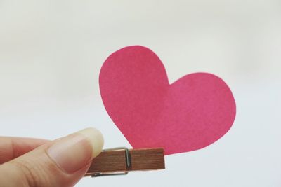 Close-up of hand holding heart shape against white background