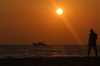 Silhouette people on sea against sky during sunset