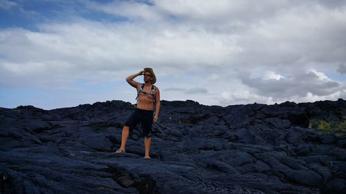 Full length of man with arms outstretched on mountain against sky