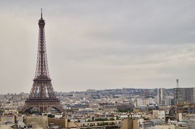 Communications tower in city against sky