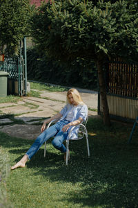 Young woman sitting on seat in yard