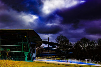 Built structure on field against storm clouds