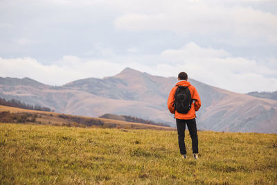 Rear view of man standing on field against sky