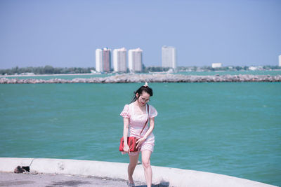 Woman standing by sea against sky