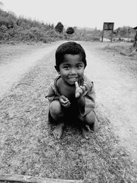 Portrait of smiling boy crouching on field