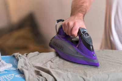 Midsection of man ironing shirt on board