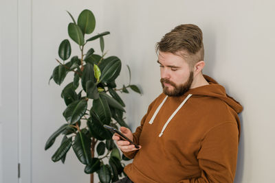 Portrait of young man standing against wall