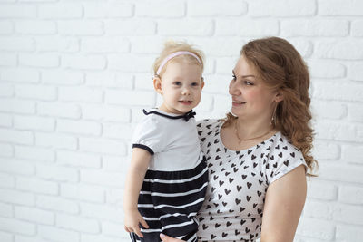 Mother with daughter against wall