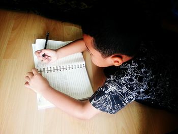 High angle view of boy holding paper on table