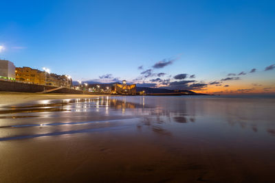 Scenic view of buildings by sea against sky during sunset