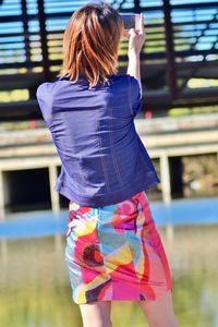 Rear view of woman photographing while standing in city