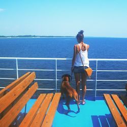 Full length of friends standing on railing against sea