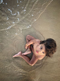 High angle portrait of woman lying on sand at beach