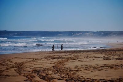 People at beach against clear sky