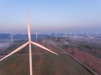 Wind turbines on field against sky