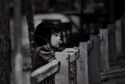 Girl standing by fence