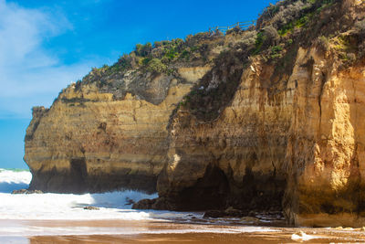 Rock formation on beach against sky