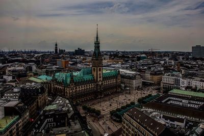 High angle view of city buildings against cloudy sky