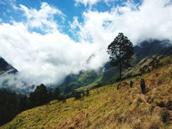 People hiking on mountains against sky