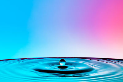 Close-up of drop falling on blue water