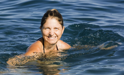 Portrait of smiling young woman swimming in sea