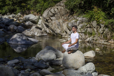 Man sitting on rock by lake