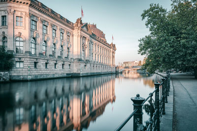 Bode-museum by spree river in city against clear sky