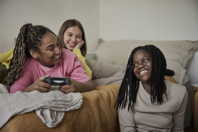 Happy female friends spending leisure time together in bedroom at home