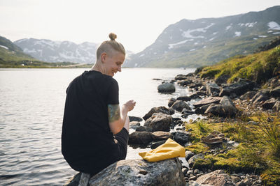 Woman sitting at lake in mountains