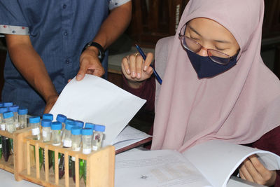 Midsection of woman reading book on table