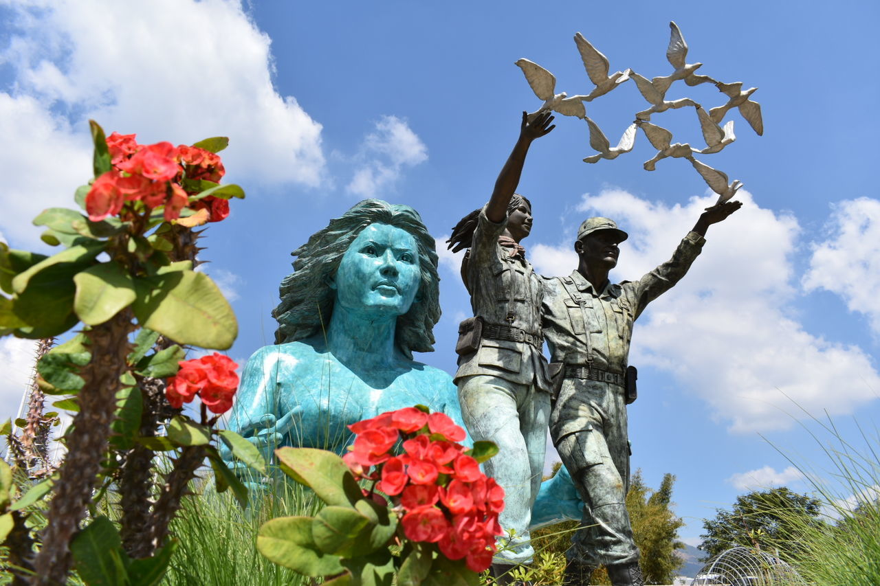 statue, human representation, sculpture, male likeness, female likeness, art and craft, low angle view, cloud - sky, craft, creativity, flower, sky, day, no people, tree, outdoors, growth, crown, nature