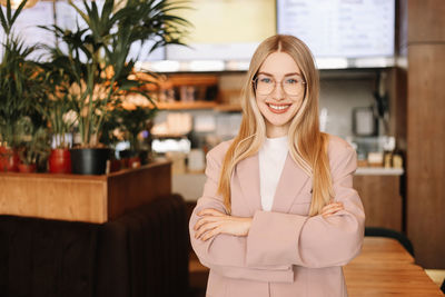 Portrait of a business woman in glasses and business clothes smiling and looking at camera in cafe