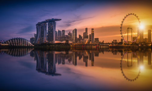 Marina bay sands by bay of water in city during sunset