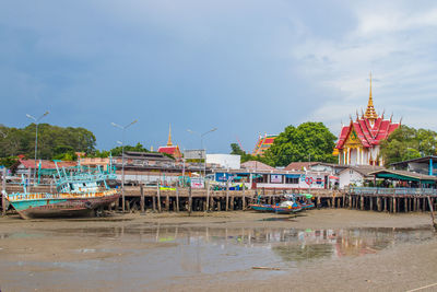 Boats in river by building against sky