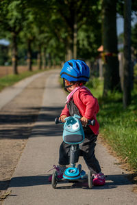 A young child with a blue bicycle helmet on a scooter