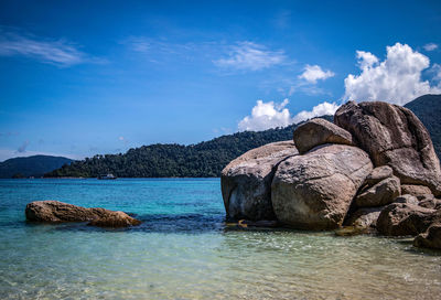 Rocks in sea against blue sky