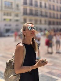 Young woman wearing sunglasses standing in city