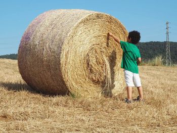 Midsection of kid with hay bales on field