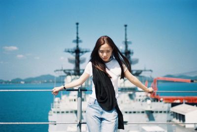 Young woman standing against blue sky