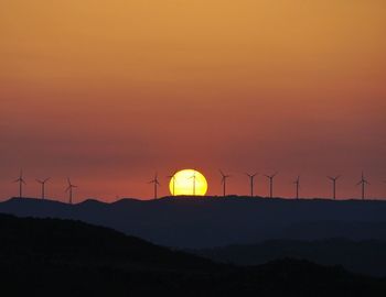 Distance shot of wind turbines on landscape at sunset