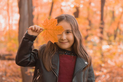 Portrait of teenage girl holding maple leaves during autumn