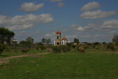 View of field against cloudy sky