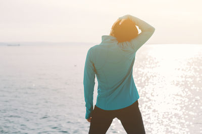 Rear view of man standing in sea against sky